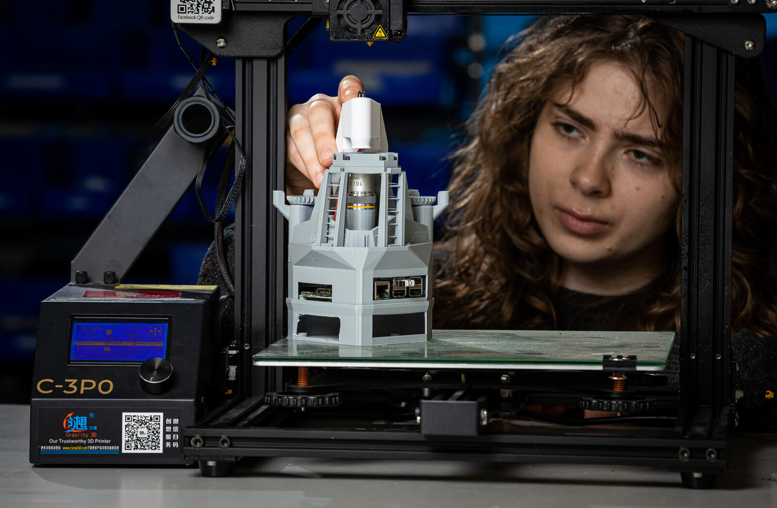 A student watches a part come off a 3D printer