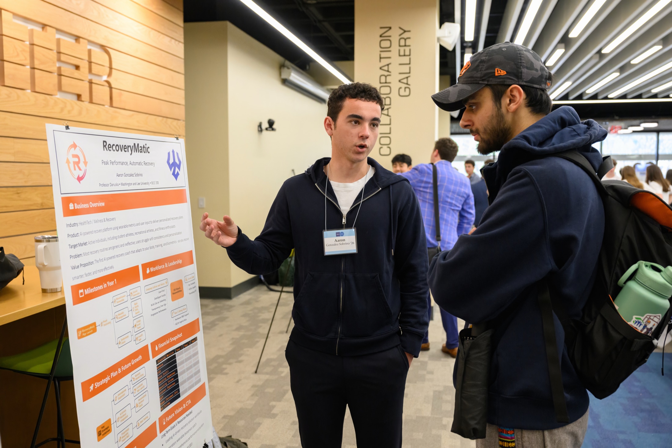 A student explains his venture poster to a visitor at the Entrepreneurship Summit showcase