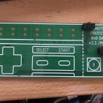 Green THOTCON 0xB badge prototype PCB laid out like an NES controller, with D-pad, Select/Start, and A/B buttons